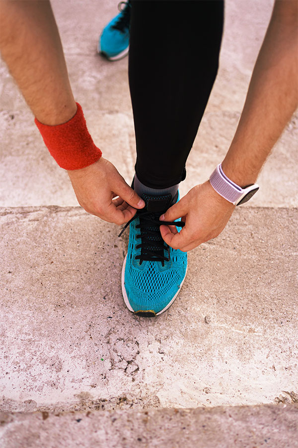 A runner lacing up a running shoe